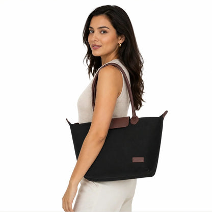 Woman holding a black tote bag with a visible brand logo on a white background